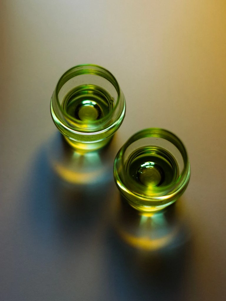 A pair of 1920s vaseline uranium glass candlestick holders, glowing faintly green
